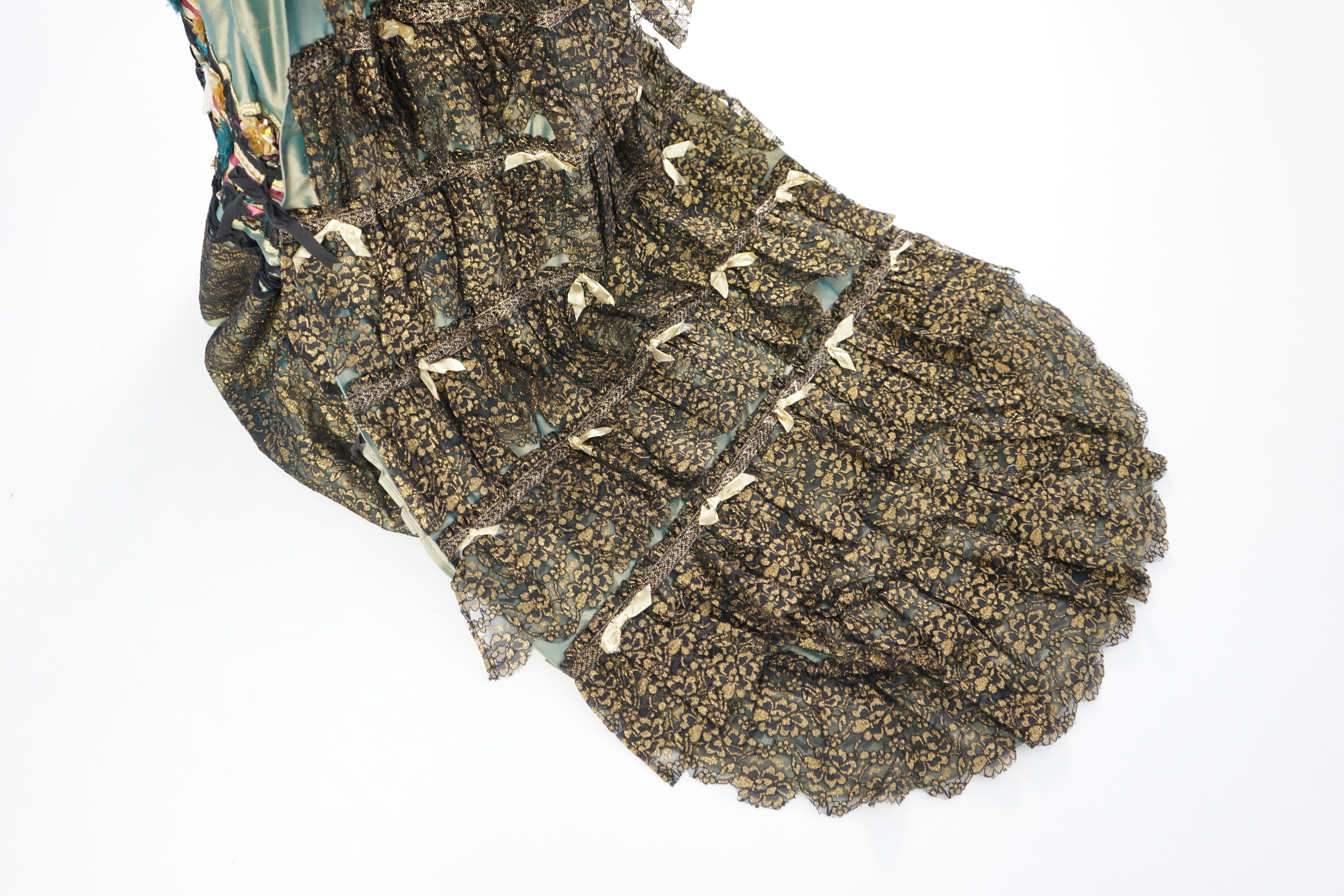 An Edwardian style lady's green taffeta skirt decorated with beaded, sequinned, ribboned border and swags of silk velvet, together with matching train layered with frilled black and gold lace, appliquéd with gold bows